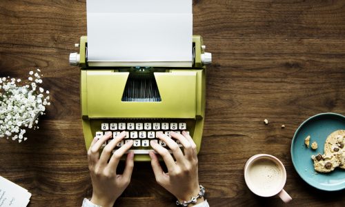 Aerial view of a woman typing on a retro typewriter blank paper Aerial view of a woman typing on a retro typewriter blank paper